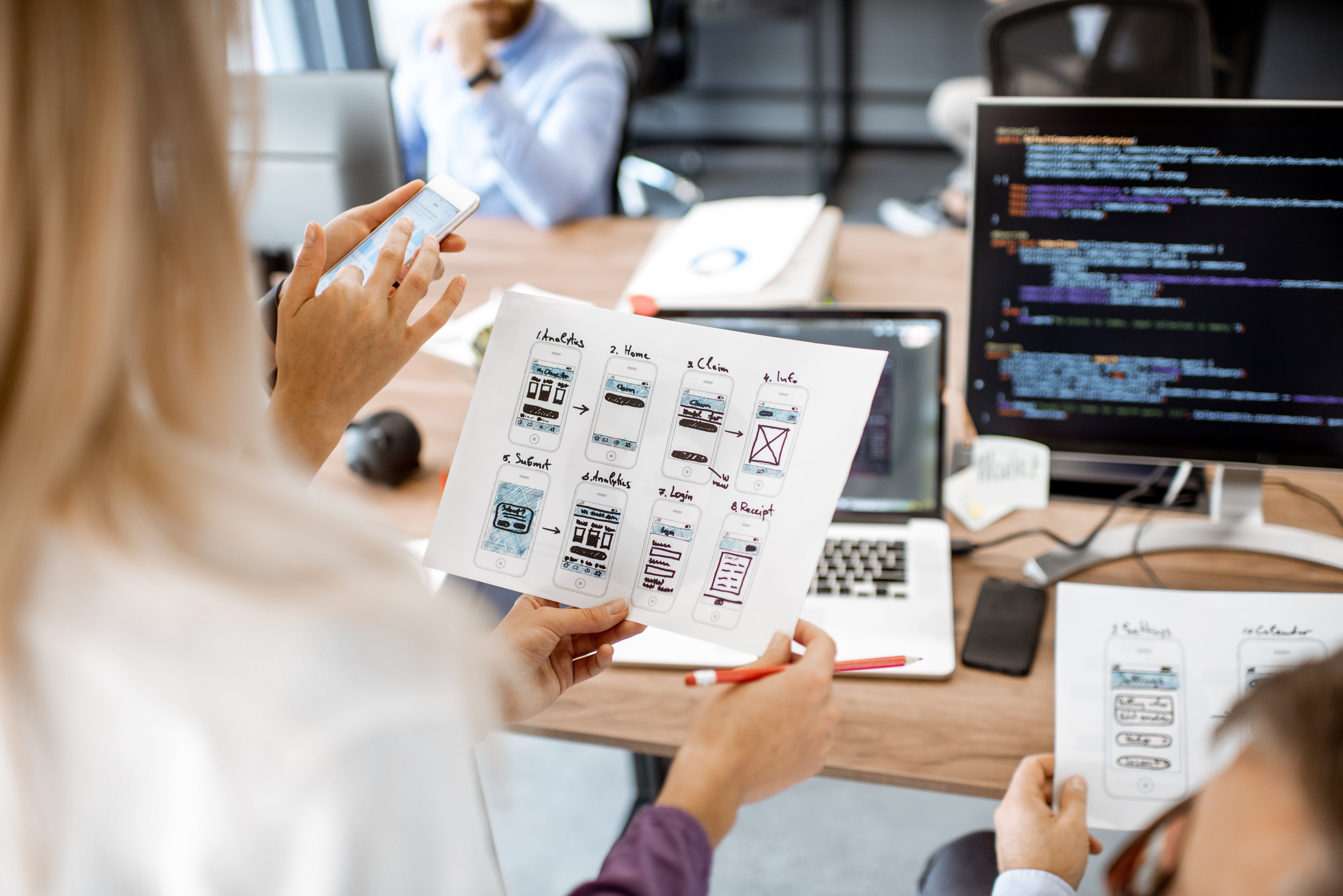 A group of people looking at phone wireframes