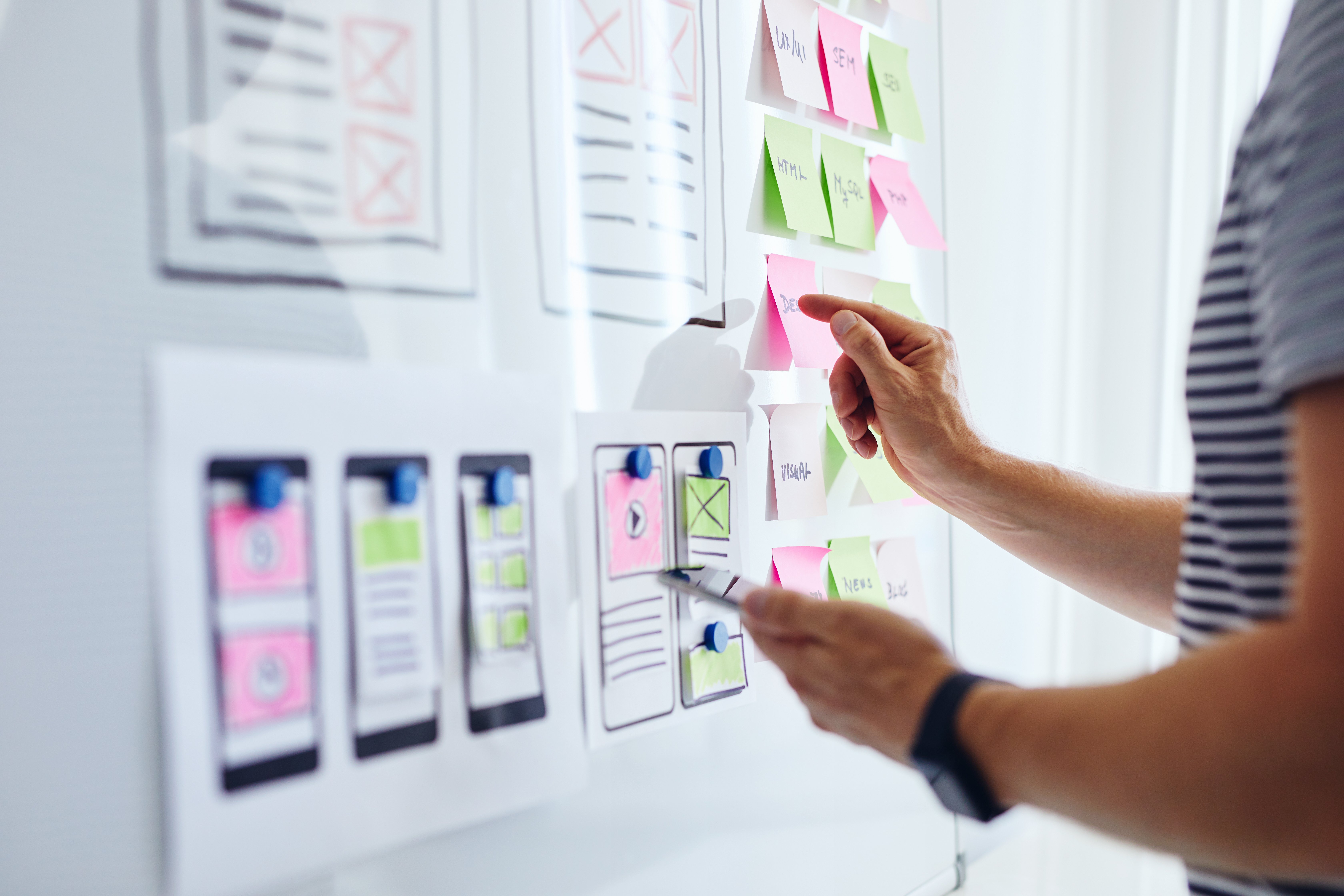 A person looking at sticky notes on a white board