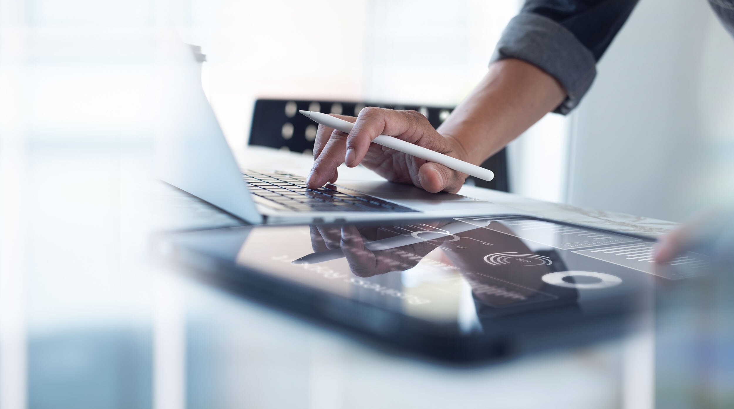 Businessman working on laptop, using mobile phone at modern office