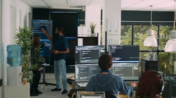 Team of software engineers analyzing code on TV