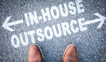 Person standing at the crossroads of in-house versus outsourcing
