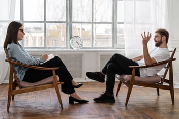 two people sitting in chairs talking