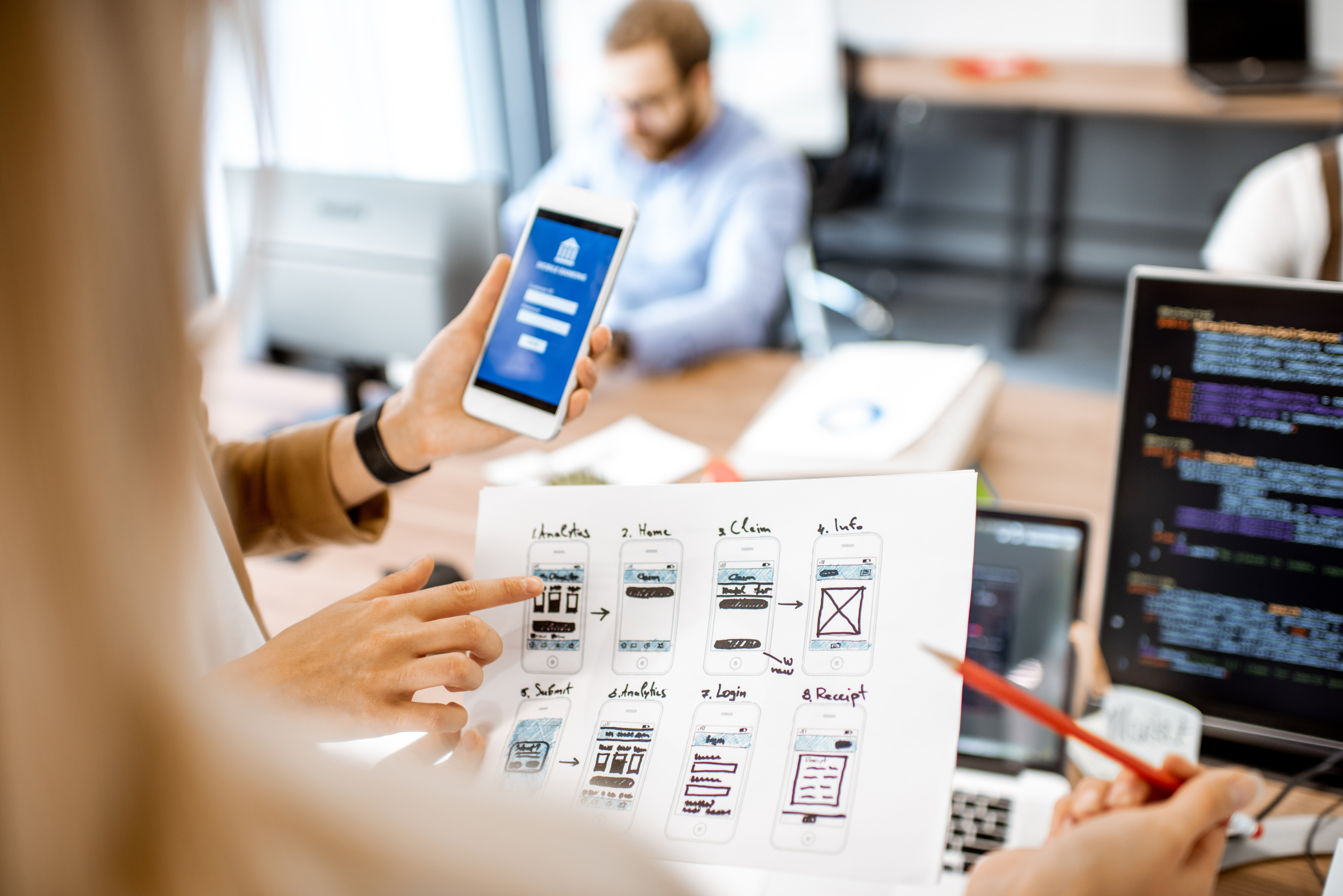 A group of people looking at a paper wireframe